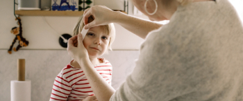 Mama doet een pleister op het hoofd van haar kindje
